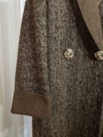Détail de la manche et du bouton doré d’un manteau marron texturé — Mesdames Akbelles