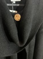 Détail du bouton doré sur cape noire en maille