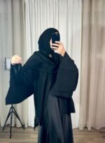 Cape noire élégante avec bouton doré portée avec hijab noir