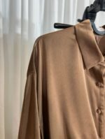 Détail de l’épaule et du col d’une chemise satinée marron — Mesdames Akbelles