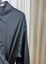 Détail de l’épaule d’une chemise noire satinée fluide