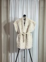gilet sans manches en fausse fourrure crème avec ceinture beige posé sur cintre
