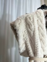 détail de l’épaule d’un gilet sans manches en fausse fourrure crème