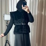 Gilet en fausse fourrure noire avec ceinture porté par une femme voilée