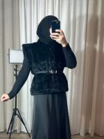 Gilet en fausse fourrure noire avec ceinture porté par une femme voilée