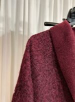 Gros plan sur la matière texturée d’une veste cardigan bordeaux