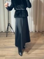 Jupe longue satinée noire fluide portée avec un gilet noir