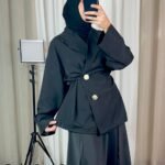 Veste noire croisée avec boutons bijoux dorés portée en tenue élégante