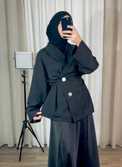 Veste noire croisée avec boutons bijoux dorés portée en tenue élégante