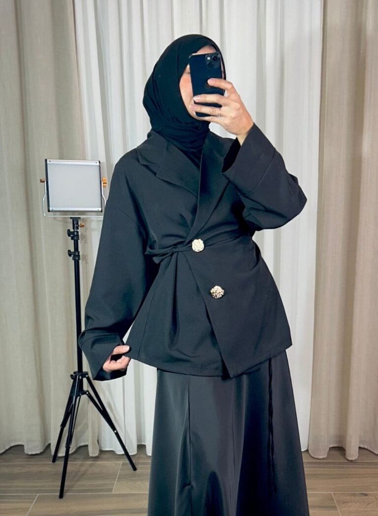 Veste noire croisée avec boutons bijoux dorés portée en tenue élégante