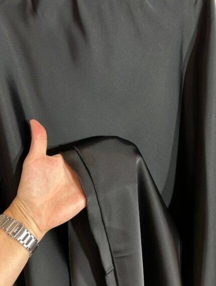 Détail du tissu satin noir fluide de la jupe longue