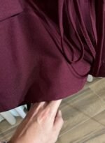 Détail du tissu et de l’ourlet d’une veste bordeaux