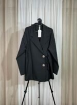 Veste noire croisée avec boutons bijoux dorés sur cintre