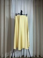 Jupe satinée fluide jaune pastel suspendue sur cintre — Mesdames Akbelles