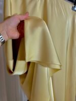 Gros plan sur le tissu satiné fluide jaune pastel d’une jupe — Mesdames Akbelles