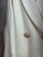 Gros plan sur le manteau crème avec boutons dorés — Mesdames Akbelles