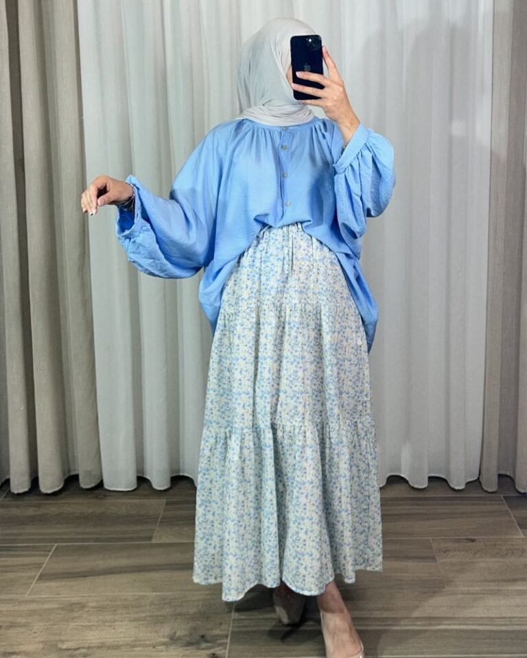 Jupe longue bohème à volants avec motif petites fleurs bleu ciel et jaune, portée avec une blouse fluide bleue et un hijab clair.