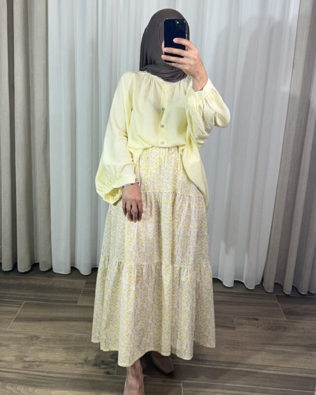 Jupe longue bohème à étages avec motif petites fleurs jaunes, portée avec une blouse fluide jaune clair et un hijab marron.