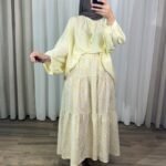 Jupe longue bohème à étages avec motif petites fleurs jaunes, portée avec une blouse fluide jaune clair et un hijab marron.