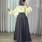 Jupe longue évasée marron chocolat à taille élastique, portée avec une chemise fluide jaune clair et un hijab marron.