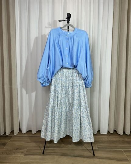 Ensemble assorti composé d'une jupe longue fleurie à étages et d'une blouse fluide bleu azur présentée sur cintre.