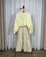 Ensemble composé d'une jupe longue fleurie jaune et d'une blouse fluide jaune pastel sur cintre.