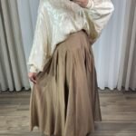 Jupe longue plissée fluide de couleur marron avec coupe évasée à volants cascade, portée avec un hijab blanc.