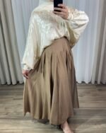 Jupe longue plissée fluide de couleur marron avec coupe évasée à volants cascade, portée avec un hijab blanc.