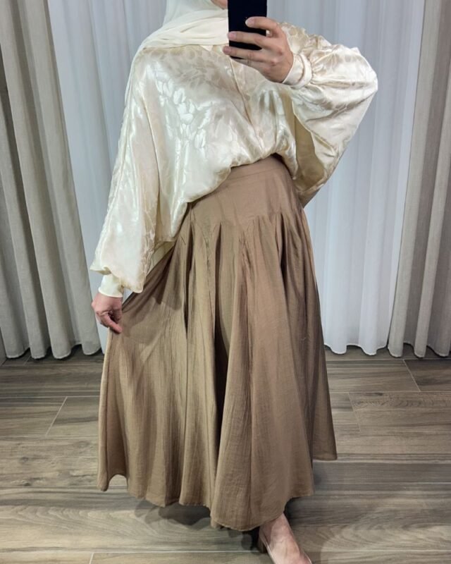 Jupe longue plissée fluide de couleur marron avec coupe évasée à volants cascade, portée avec un hijab blanc.