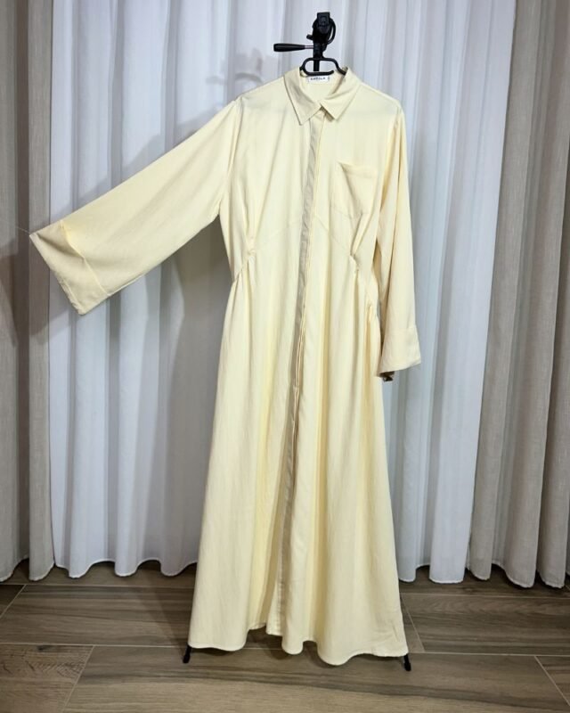 Robe longue fluide jaune clair sur cintre avec col chemise, boutons et poche sur la poitrine.