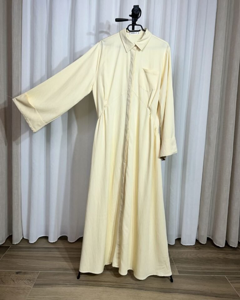 Robe longue fluide jaune clair sur cintre avec col chemise, boutons et poche sur la poitrine.