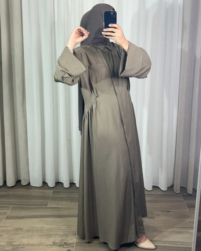 Robe longue style chemise couleur taupe avec manches longues évasées, portée de profil.