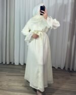 Robe longue style chemise couleur crème pastel avec motifs fins, ceinture nouée à la taille et poignets à volants cascade.