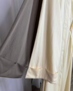 Zoom sur le tissu et les manches évasées de la robe longue en coloris taupe et crème.