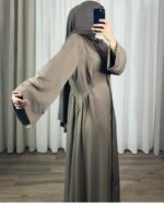 Robe longue style chemise couleur taupe portée avec un hijab assorti devant un miroir.