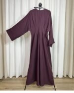 Robe longue de couleur aubergine foncée sur cintre, montrant les détails des plis à la taille et la coupe évasée.